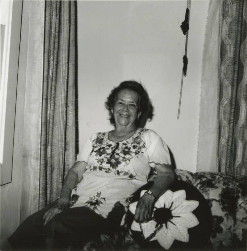 Unidentified woman sits on couch & poses for camera (1 of 2)