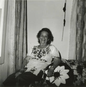 Unidentified woman sits on couch & poses for camera (1 of 2)