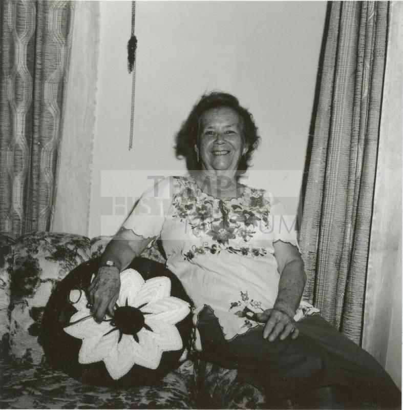 Unidentified woman sits on couch & poses for camera (2 of 2)
