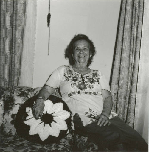 Unidentified woman sits on couch & poses for camera (2 of 2)