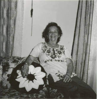 Unidentified woman sits on couch & poses for camera (2 of 2)