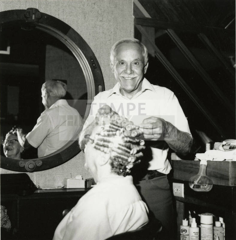 Man setting curlers for seated woman