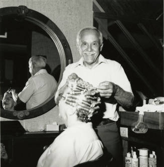 Man setting curlers for seated woman