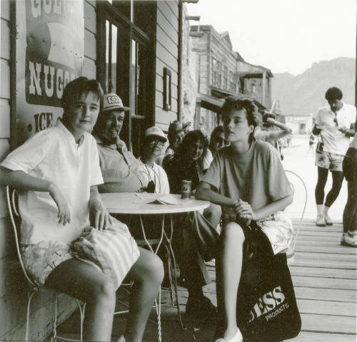 A group of people sit outside around a table posing for a picture