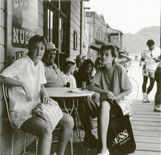A group of people sit outside around a table posing for a picture