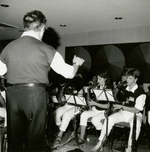 A conductor leads a section of saxophone players.
