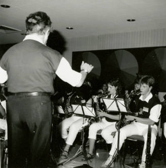 A conductor leads a section of saxophone players.