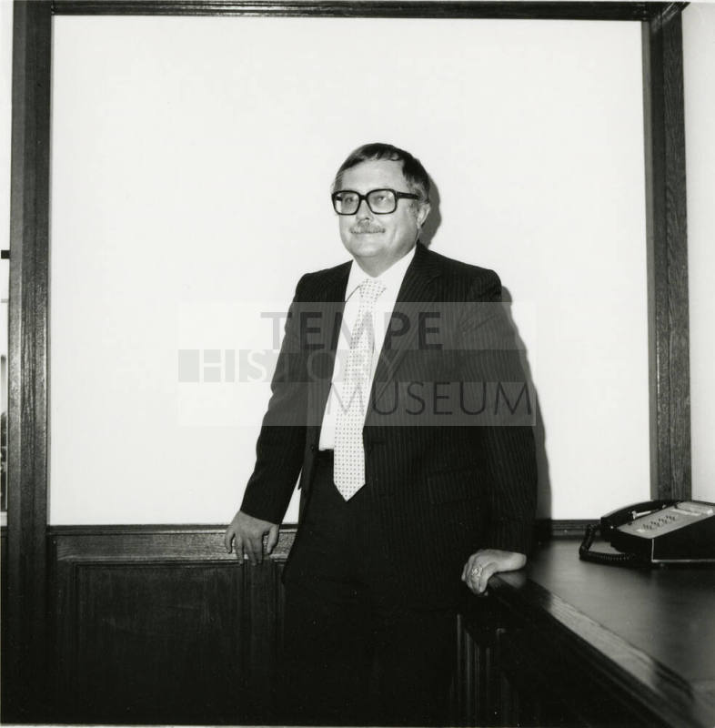 Man dressed in business attire in front of a classroom/meeting white board (1of 2)