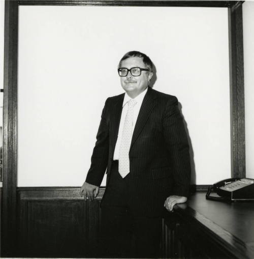 Man dressed in business attire in front of a classroom/meeting white board (1of 2)