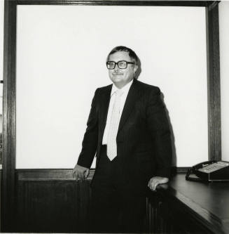 Man dressed in business attire in front of a classroom/meeting white board (1of 2)
