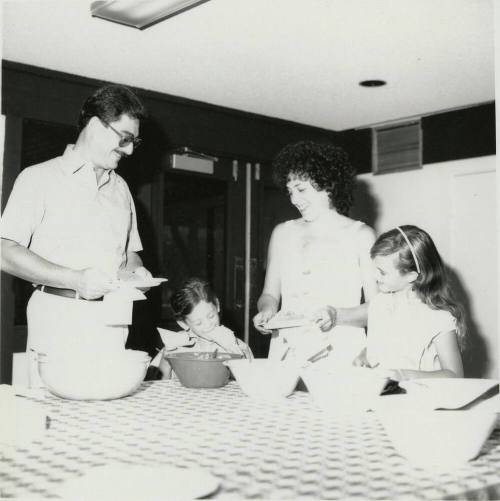 Unidentified family standing at a table sampling food