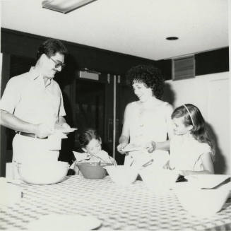 Unidentified family standing at a table sampling food