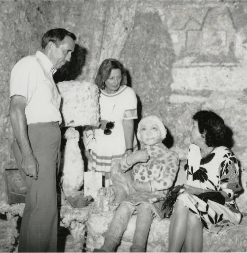 Three unidentified people in a mock room with a mock person