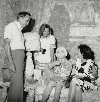 Three unidentified people in a mock room with a mock person