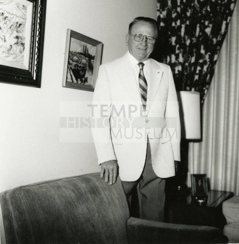Unidentified man standing behind a chair