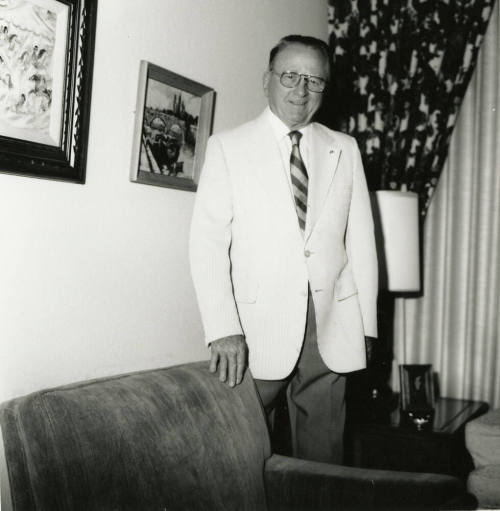 Unidentified man standing behind a chair