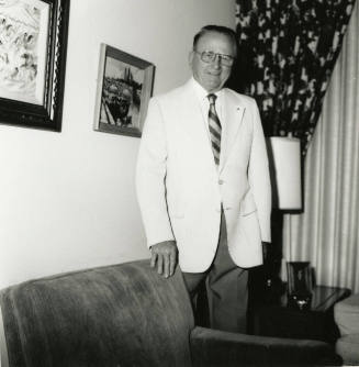 Unidentified man standing behind a chair