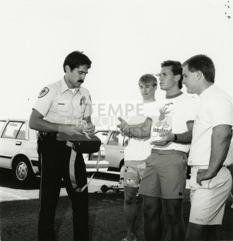 3 young men and a cop in a parking lot