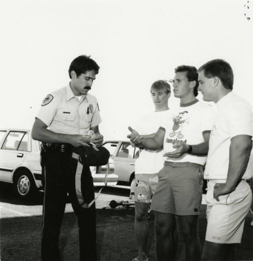 3 young men and a cop in a parking lot