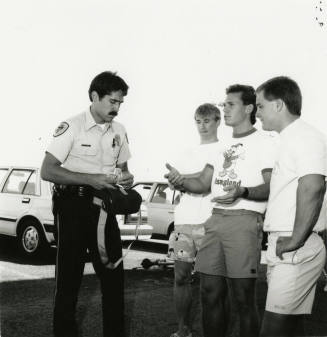 3 young men and a cop in a parking lot