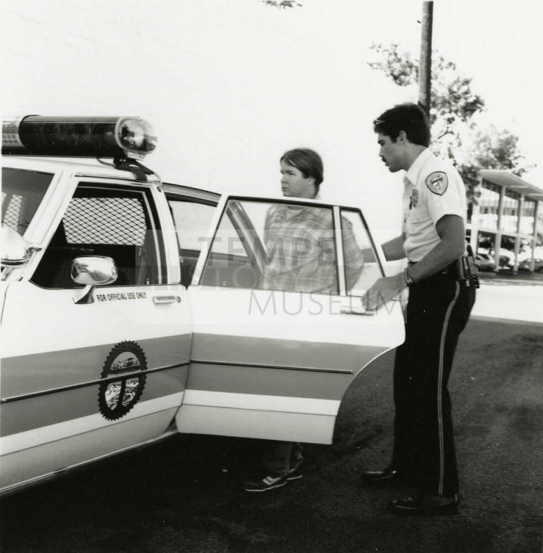 Unidentified Man Put into Police Car by Officer