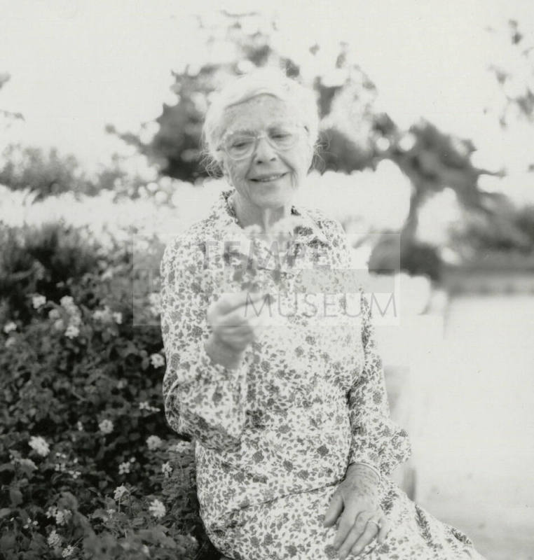 Older woman admires a section of lantana plant