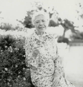 Older woman admires a section of lantana plant
