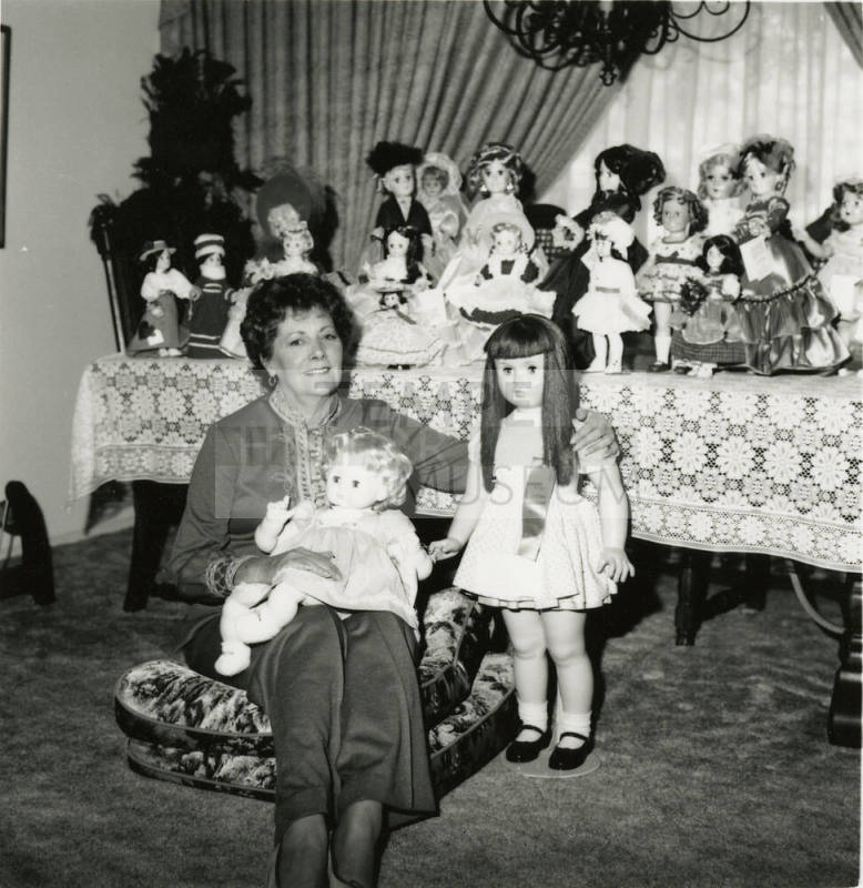Woman seated on the floor with doll collection