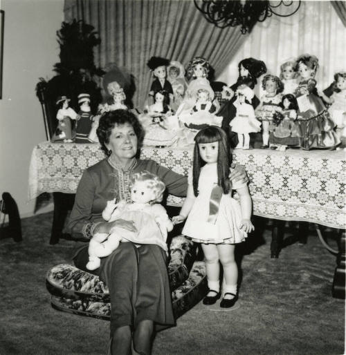 Woman seated on the floor with doll collection