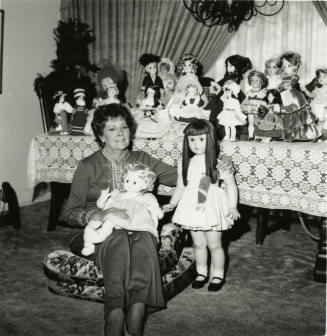 Woman seated on the floor with doll collection