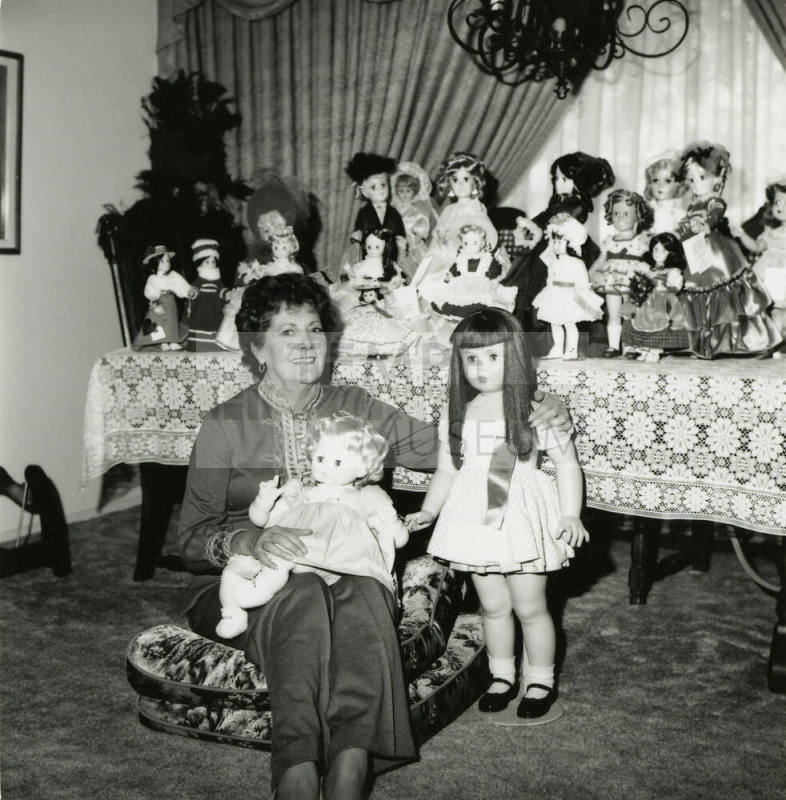 Woman seated on the floor with doll collection