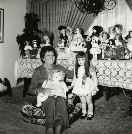 Woman seated on the floor with doll collection