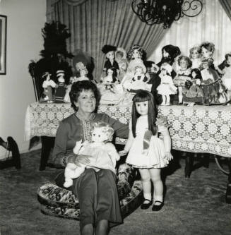 Woman seated on the floor with doll collection