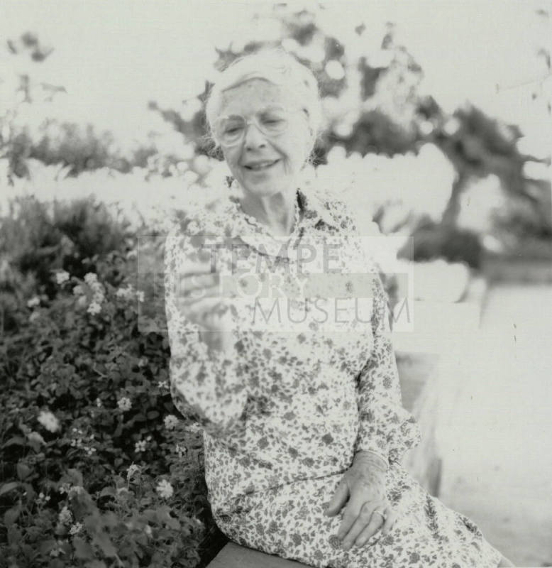Older woman admires a section of lantana plant