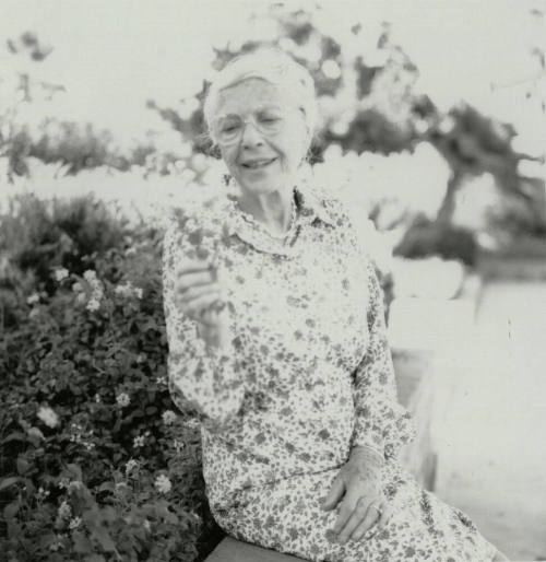 Older woman admires a section of lantana plant