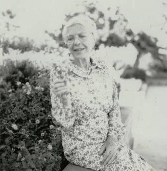Older woman admires a section of lantana plant
