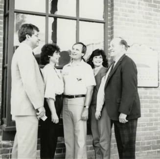 Three unidentified people, Harry Mitchell (center), and Richard Neuheisel (left) at the Hackett House