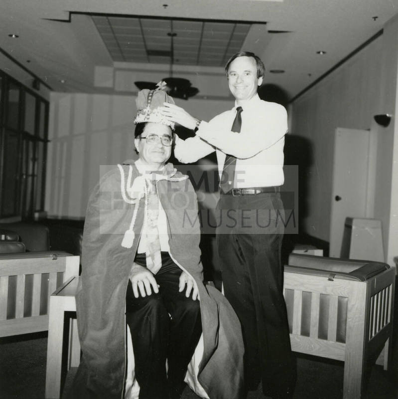 Harry Mitchell putting crown on a mans head.