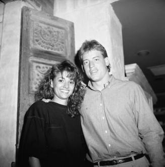 young man and woman pose in front of carved door