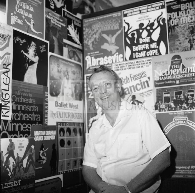 Man poses in front of wall of peforming arts posters