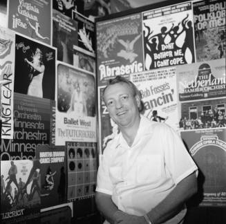 Man poses in front of wall of peforming arts posters
