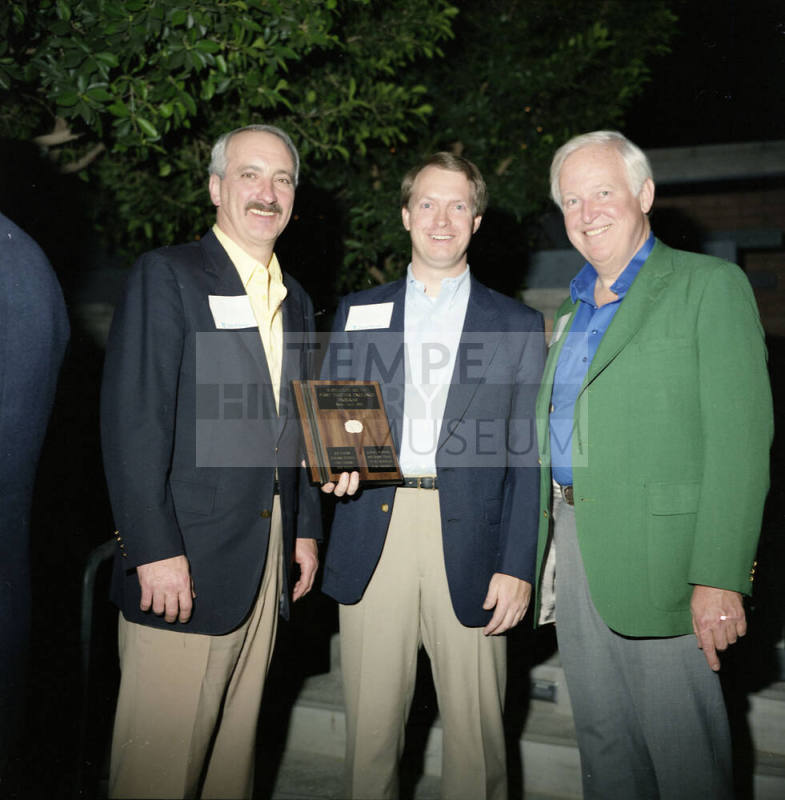 Three gentleman holding a plaque