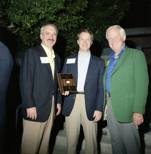 Three gentleman holding a plaque