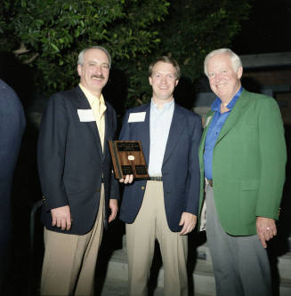 Three gentleman holding a plaque