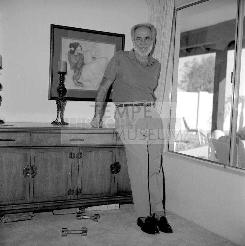 Middle aged man in Home leaning against chest by window