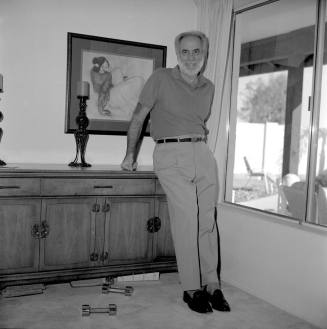 Middle aged man in Home leaning against chest by window