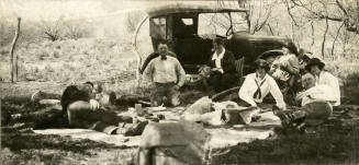 Photograph of people lying near a vehicle