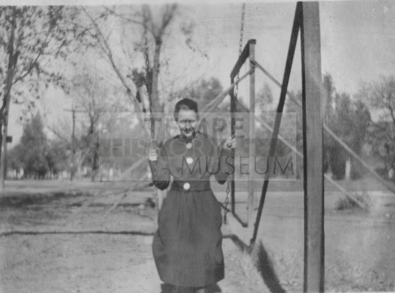 Woman in a dress sitting on a swing.