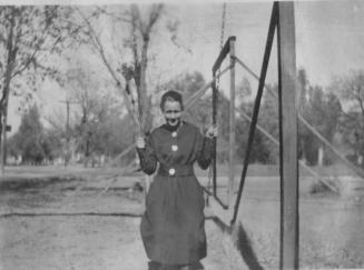 Woman in a dress sitting on a swing.
