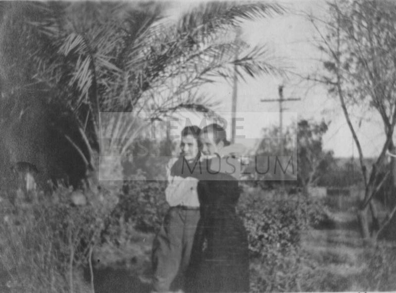 Girls hug near palm trees